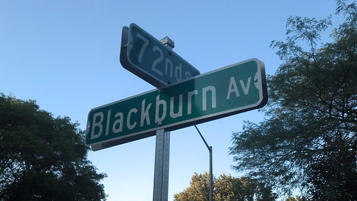 A perpendicular pair of street signs, one reading Blackburn Av, and the other reading 72nd St. The signs are mixed-case, rather than all caps.